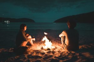 Man and Woman talking at fire on beach